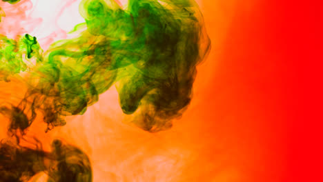 Green-And-Orange-Paint-Or-Dye-Dropped-Into-Water-Against-White-Background-To-Create-Swirling-Colourful-Smoke-Background